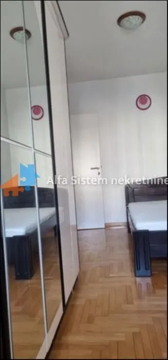 Spavaća soba sa krevetom i ormarom sa ogledalom.