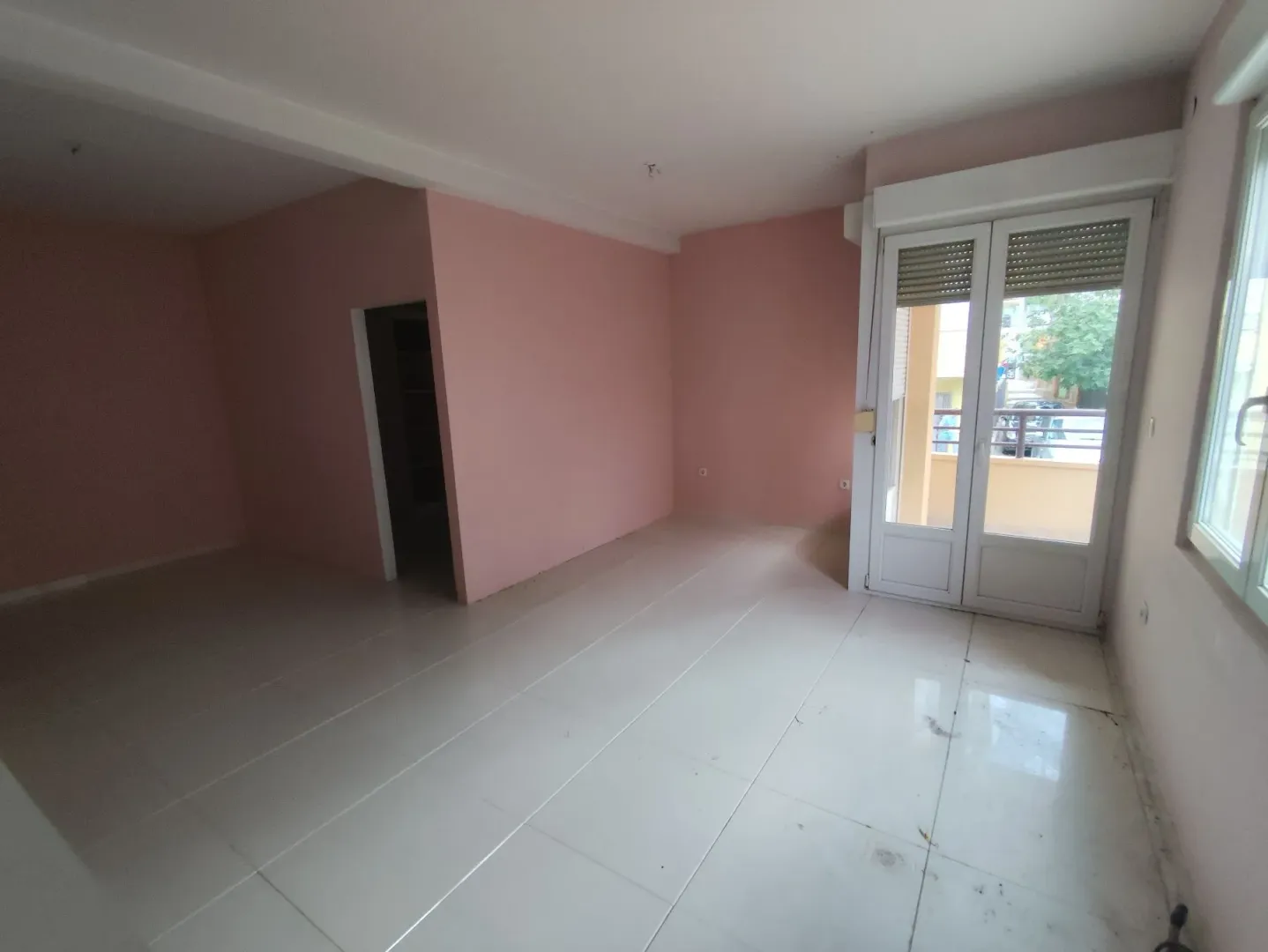Prazna soba sa roze zidovima i keramičkim pločicama na podu.