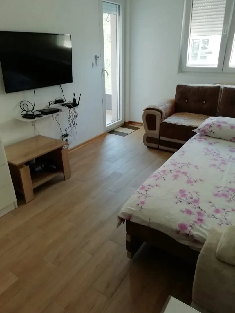 Namještena spavaća soba sa krevetom, trosjedom i televizorom na zidu.