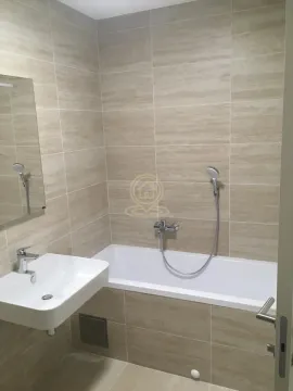 Bathroom equipped with a bathtub, washbasin, and mirror, tiled in beige ceramic tiles. - image 2