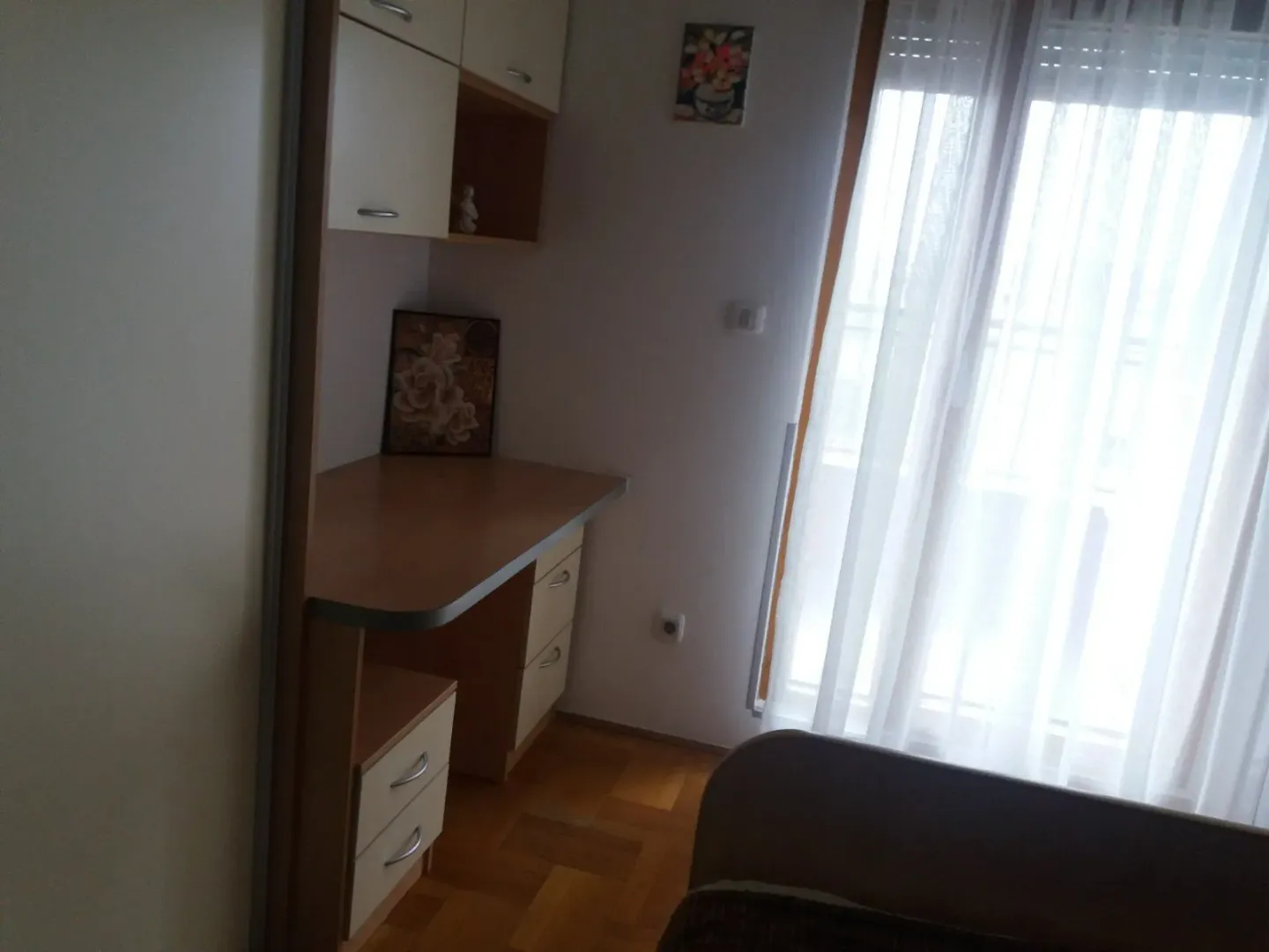 A room with a study desk, wardrobe, and a window with curtains.