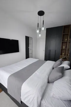 Modern bedroom with a double bed, black wardrobe, and wall-mounted TV. - image 7