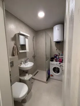 Smaller bathroom with a walk-in shower, washbasin, and washing machine. - image 4
