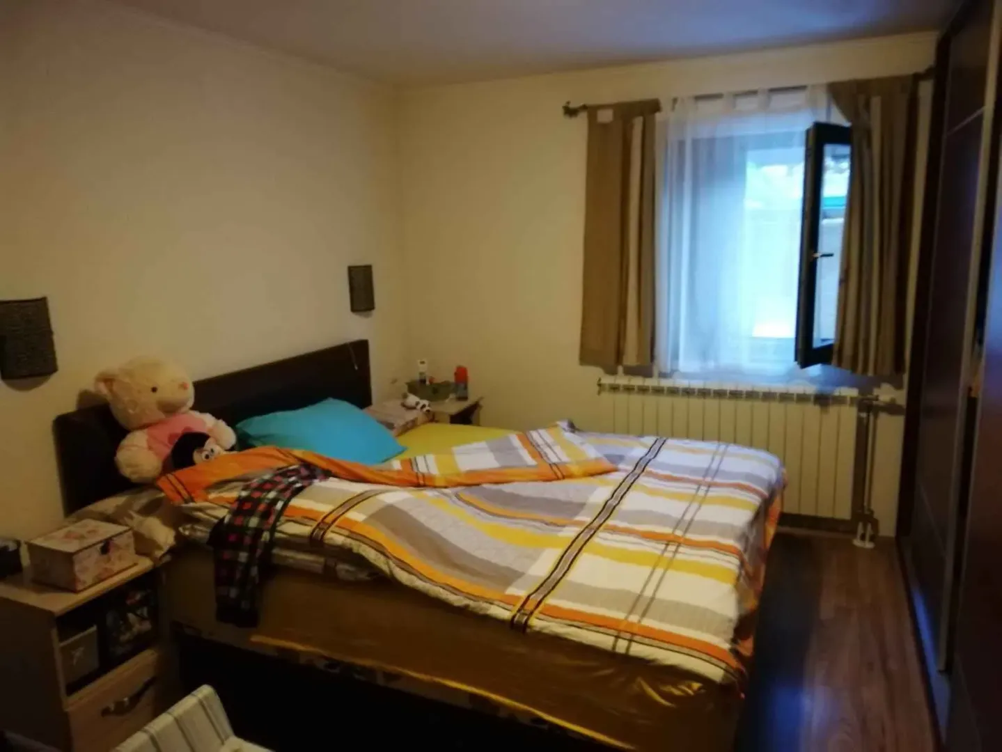 Namještena spavaća soba sa bračnim krevetom, prozorom i ormarom.