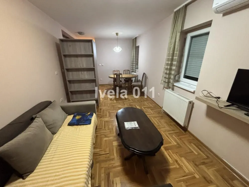 Dnevna soba sa garniturom, stočićem i trpezarijskim delom u pozadini.