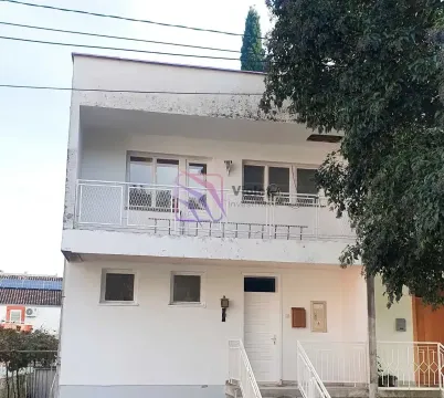Prednji pogled na višespratnu kuću sa balkonom i ulaznim vratima. - image 7
