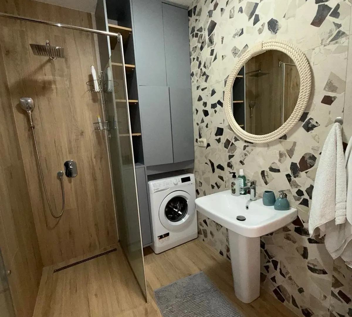 Modernly equipped bathroom with a shower cabin, washbasin, and washing machine.