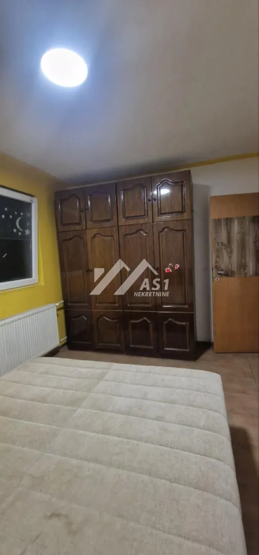 Nameštena spavaća soba sa velikim drvenim ormarom i krevetom.