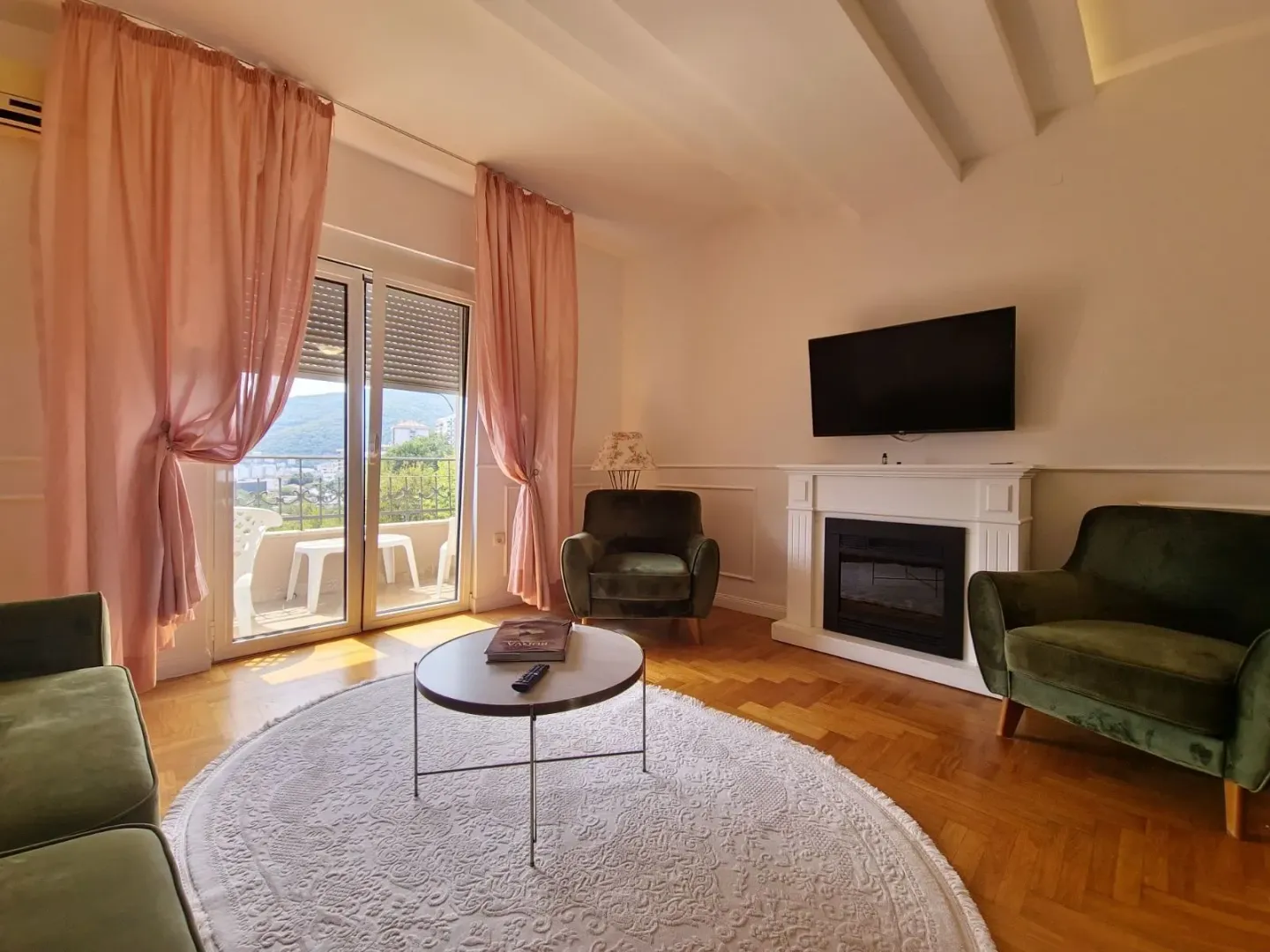 Living room with armchairs, fireplace, TV, and access to the terrace.