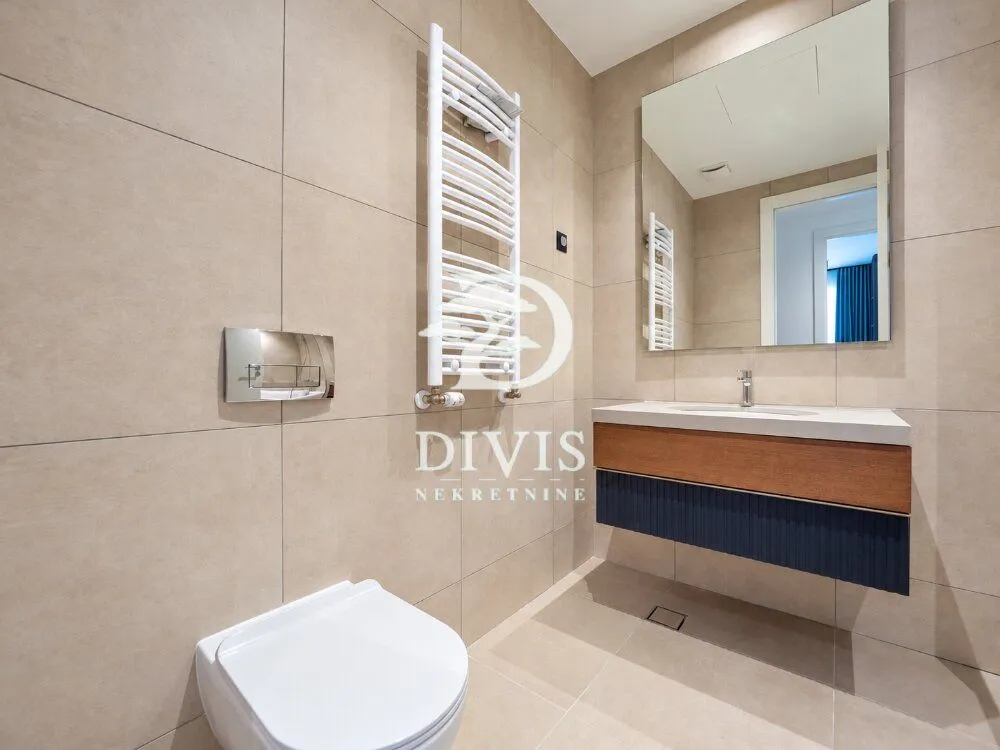 Modern bathroom with a wall-hung toilet, vanity sink, and towel radiator.