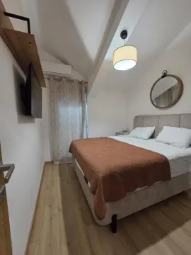 Smaller bedroom with a double bed, TV, and a round wall mirror. - image 11