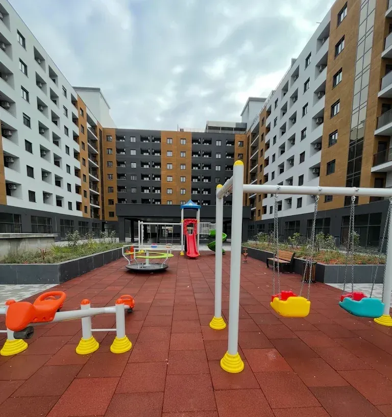 Dvorište stambene zgrade sa dječijim igralištem.
