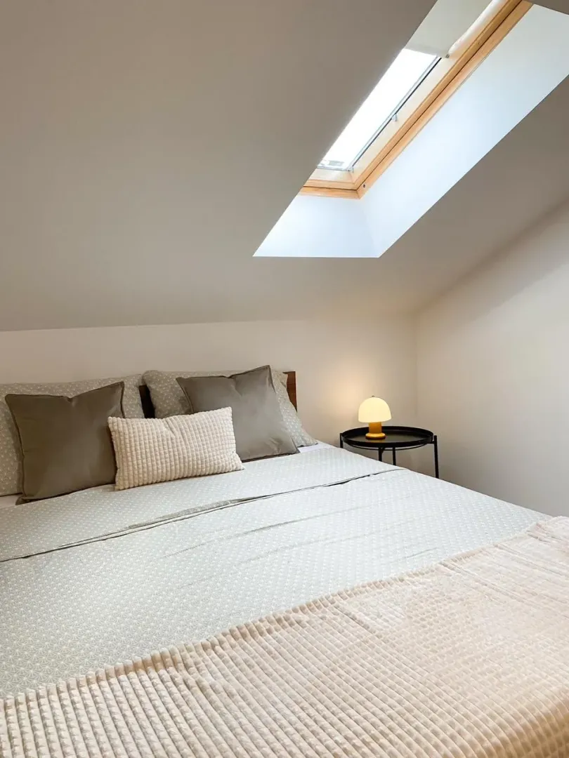 Attic bedroom with a double bed and a skylight window.