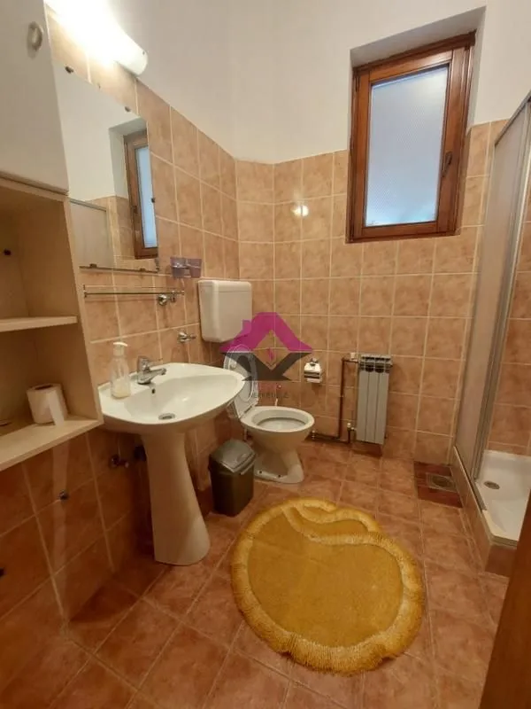 Kupatilo obloženo keramičkim pločicama sa umivaonikom, WC šoljom i tuš kabinom.