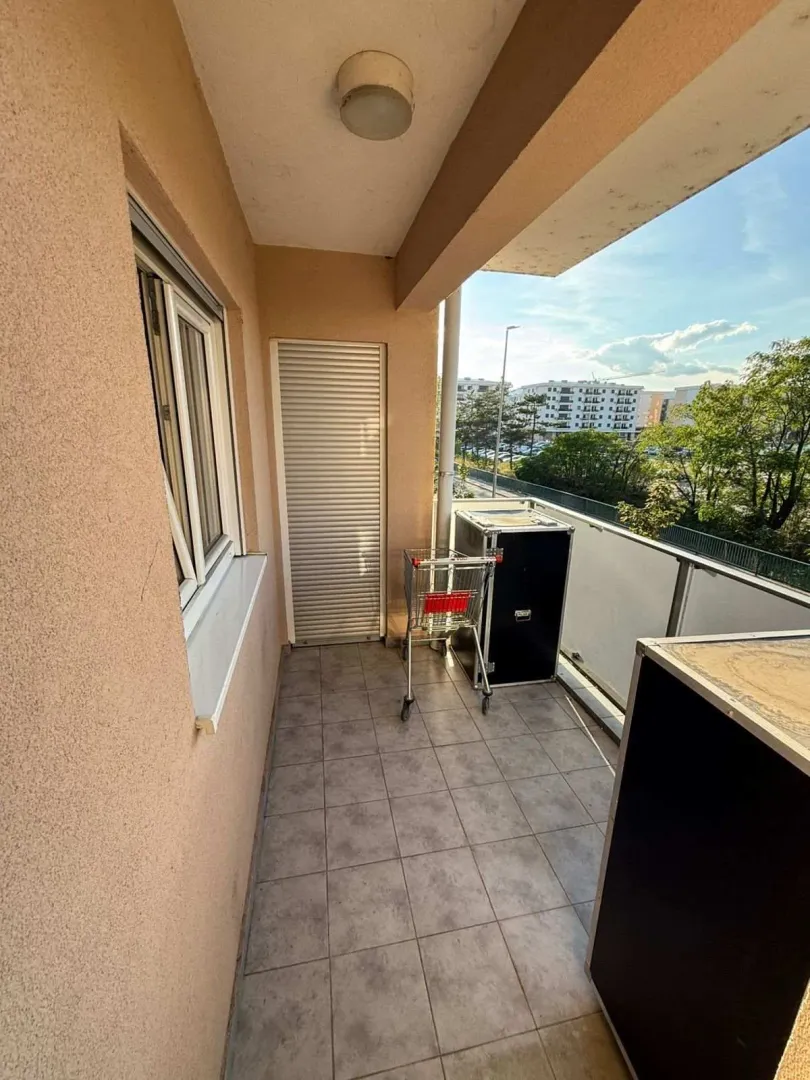 Natkriveni balkon sa popločanim podom i pogledom na okolinu.