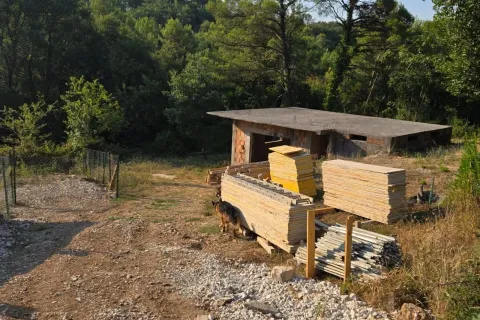 Nedovršeni objekat sa građevinskim materijalom u dvorištu okruženom šumom. - image 6
