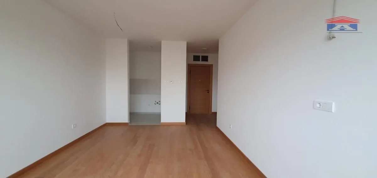 An empty room with wooden flooring and white walls.
