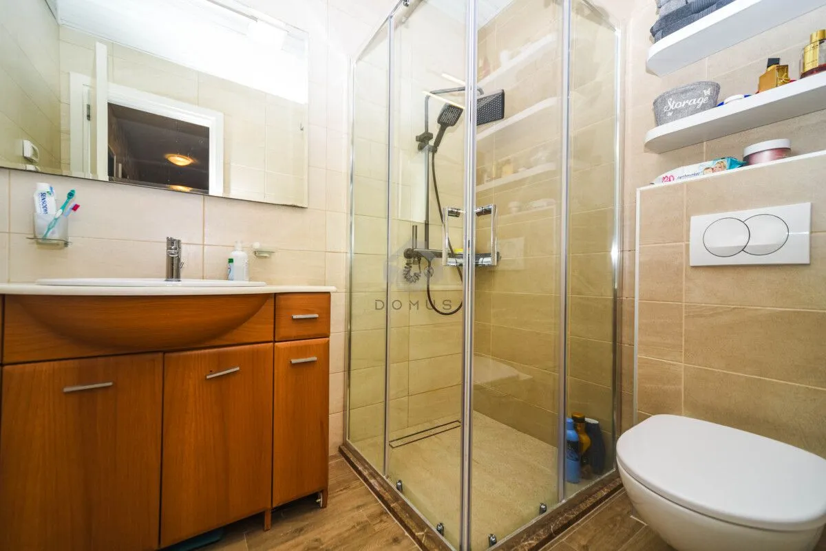 Moderne kupatilo sa tuš kabinom, umivaonikom i ugradnom wc šoljom.
