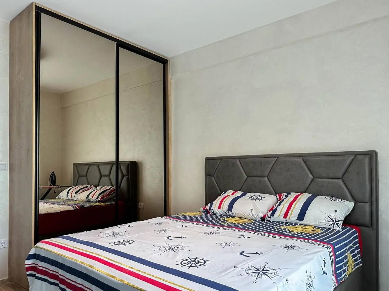 Furnished bedroom with a large double bed and a mirrored wardrobe.