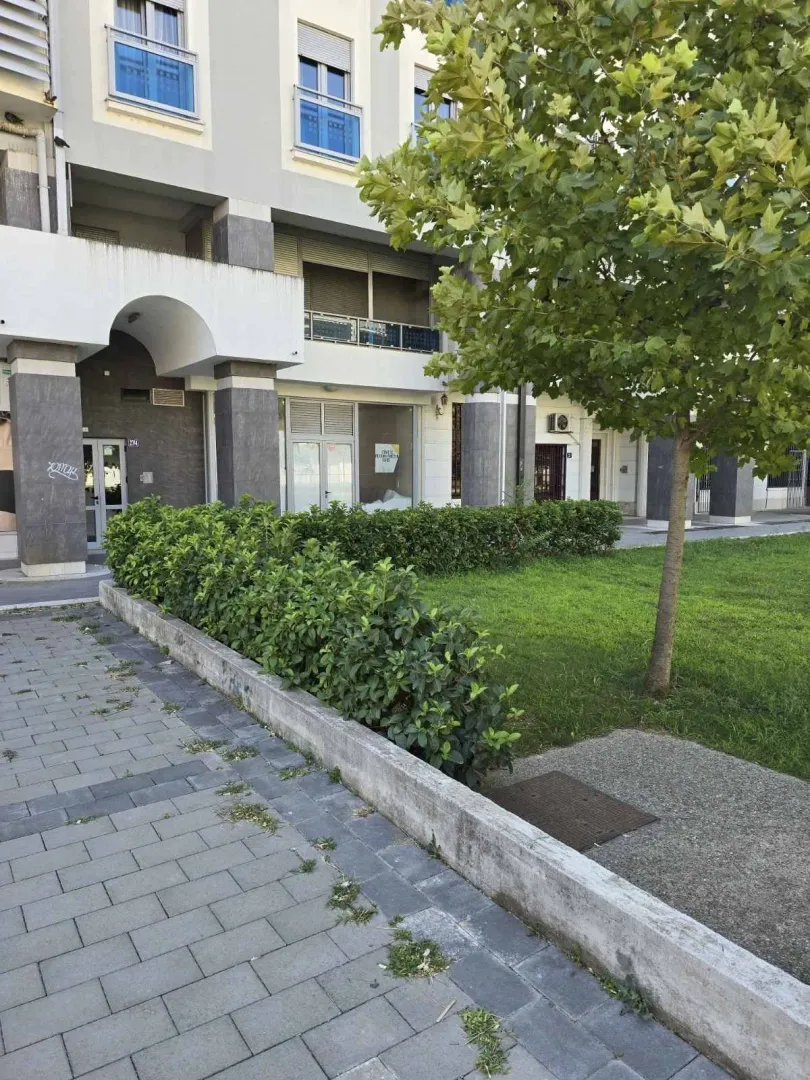 Exterior of a residential building with landscaped greenery and a paved path.