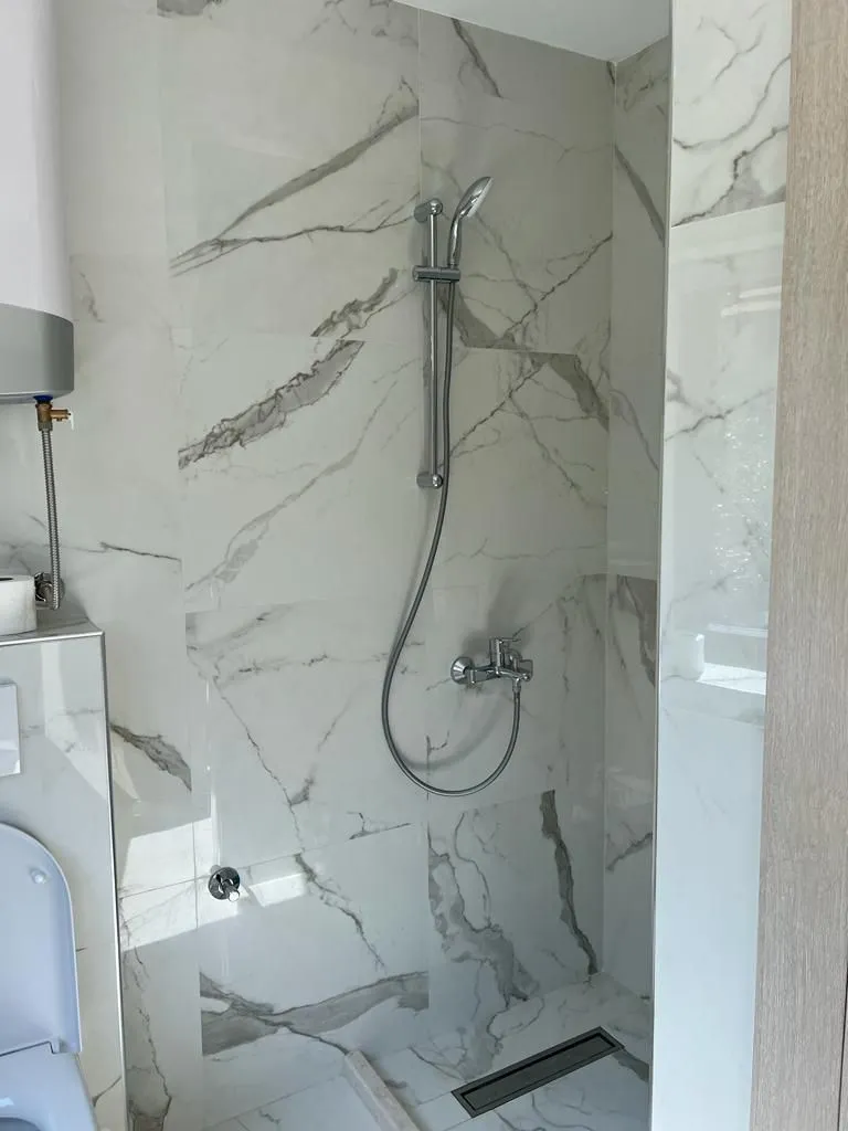 Bathroom with a walk-in shower lined with marble tiles.
