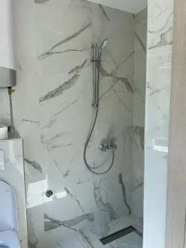Bathroom with a walk-in shower lined with marble tiles. - image 3