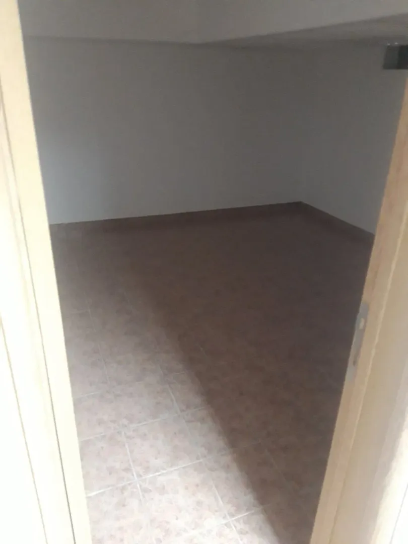 An empty room with light tiles viewed through an open doorway.