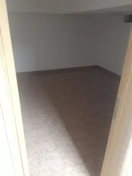 An empty room with light tiles viewed through an open doorway. - image 3