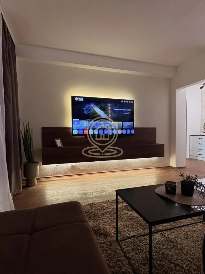 Dnevna soba sa TV-om, zidnom komodom i stočićem.