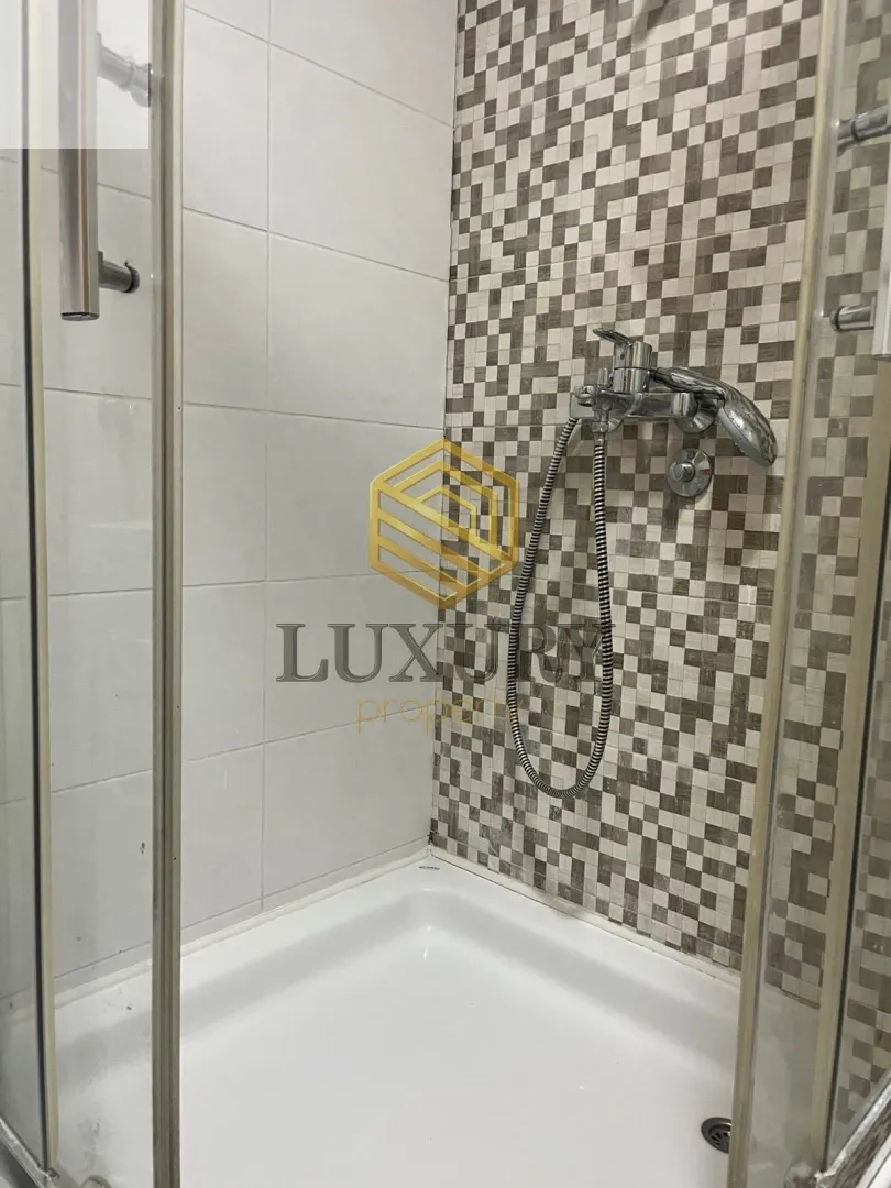 Small shower cabin with mosaic tiles and a faucet.