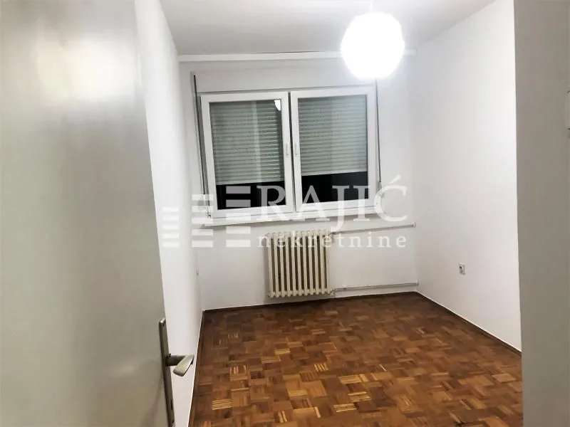 Empty room with parquet flooring and a window.