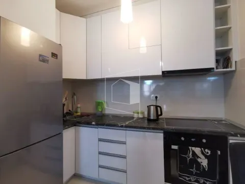 Moderna kuhinja sa bijelim elementima, tamnom radnom površinom i ugradnim uređajima. - image 4