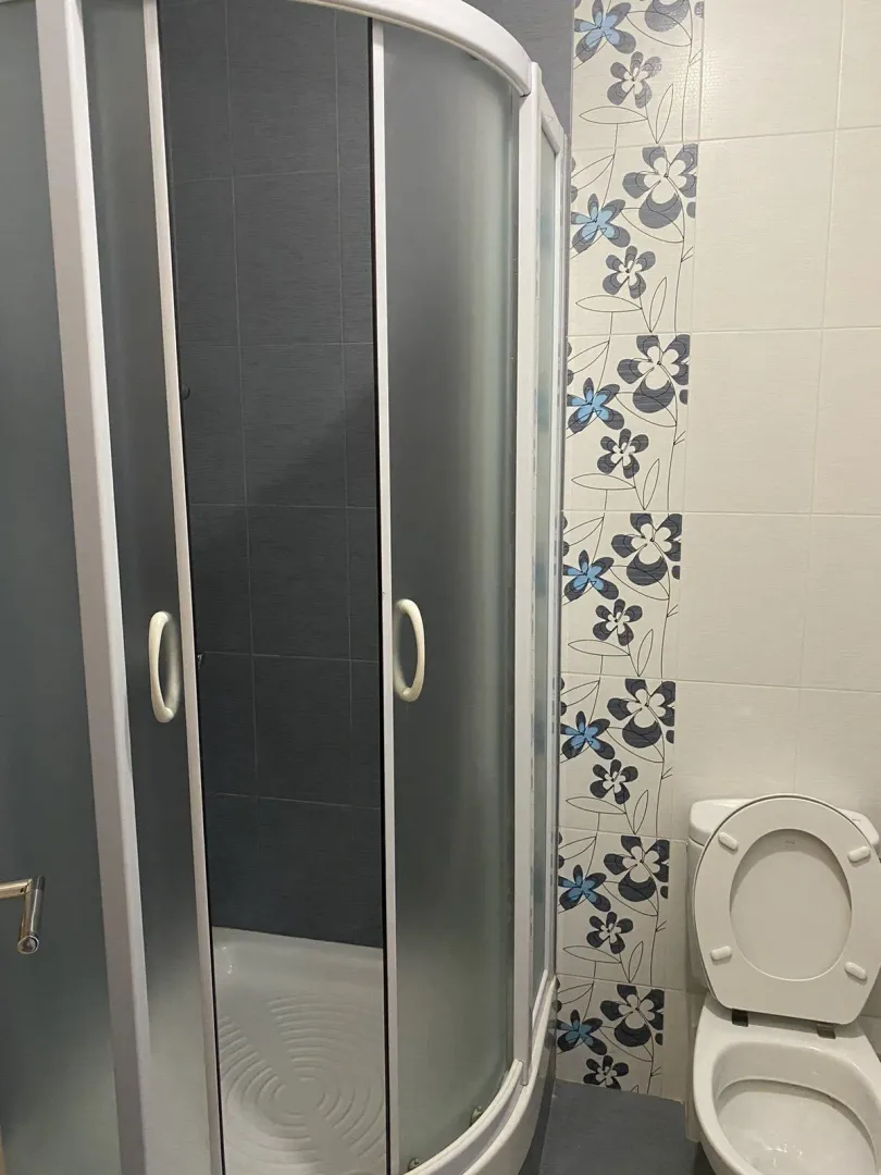 Kupatilo sa tuš kabinom i dekorativnim pločicama.
