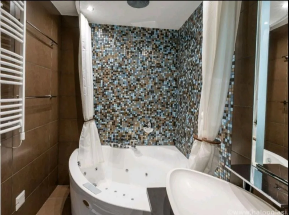 Modern bathroom with a corner whirlpool bathtub and a washbasin.