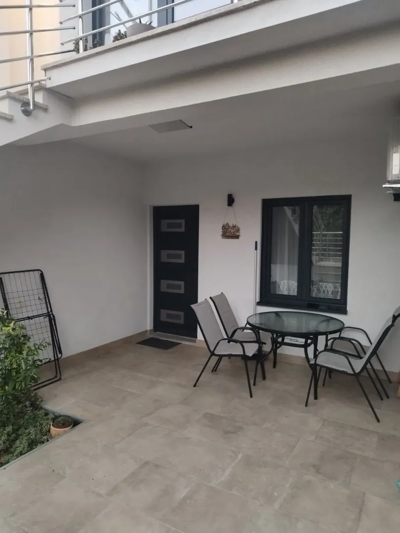 Natkriveni popločani ulazni dio kuće sa garniturom za sjedenje.