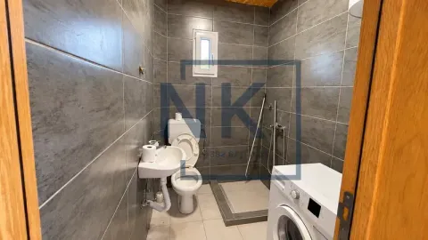 Kupatilo obloženo sivim pločicama sa tuš kabinom, WC šoljom, umivaonikom i veš mašinom. - image 6