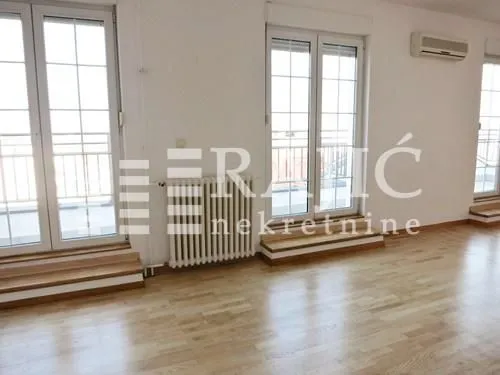 Spacious empty room with parquet flooring and balcony doors.