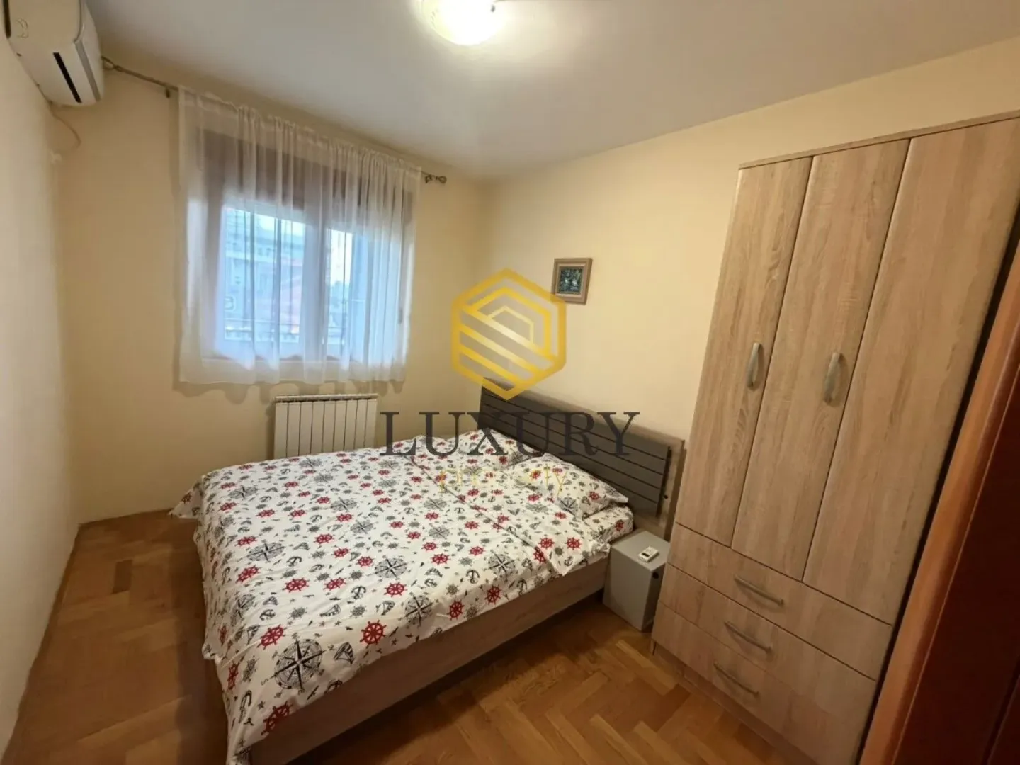 Namještena spavaća soba sa bračnim krevetom i ormarom.