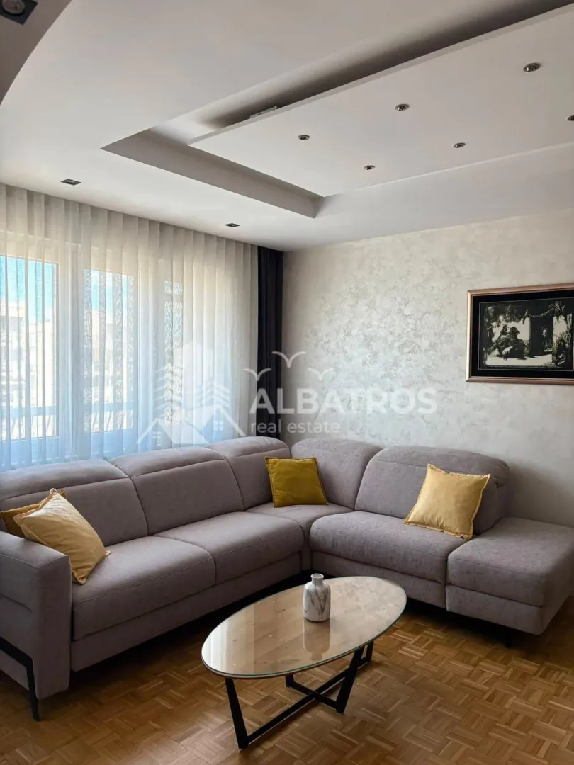 Living room with a corner sofa, coffee table, and dropped ceiling with lighting.