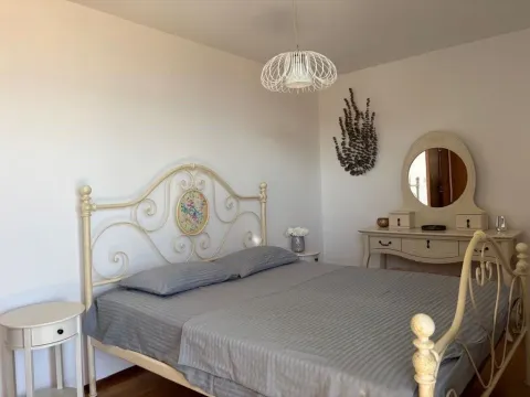 Svjetla spavaća soba sa bračnim krevetom, bijelim noćnim stočićem i toaletnim stočićem sa ogledalom. - image 3