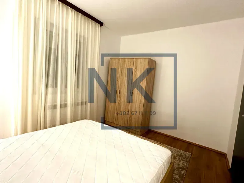 Bedroom with a double bed, wardrobe, and a window with curtains.