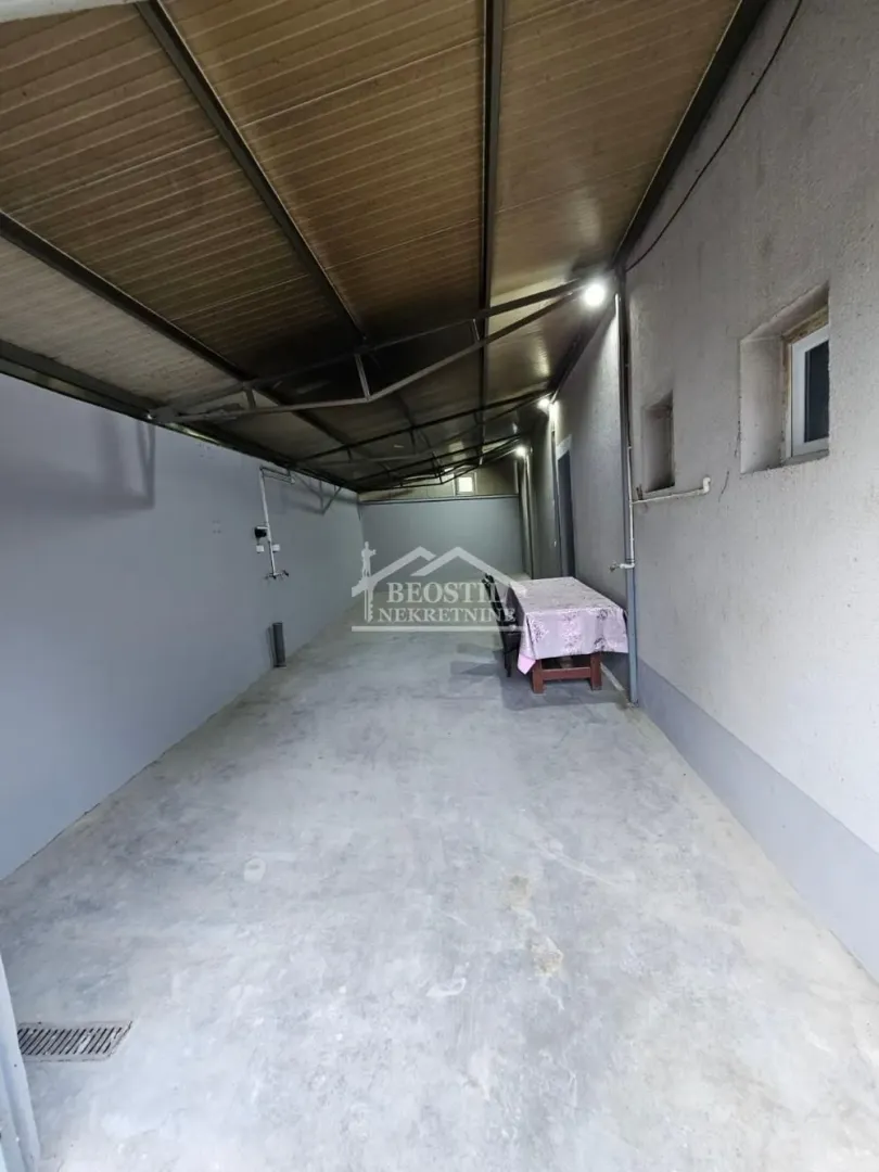 Covered outdoor space with a table and benches next to the building.