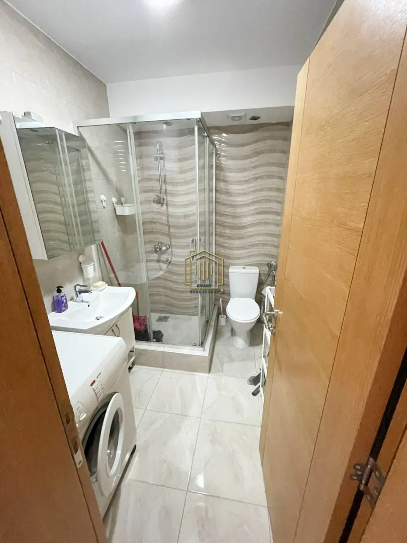 Small bathroom with a shower cabin, sink, and washing machine.