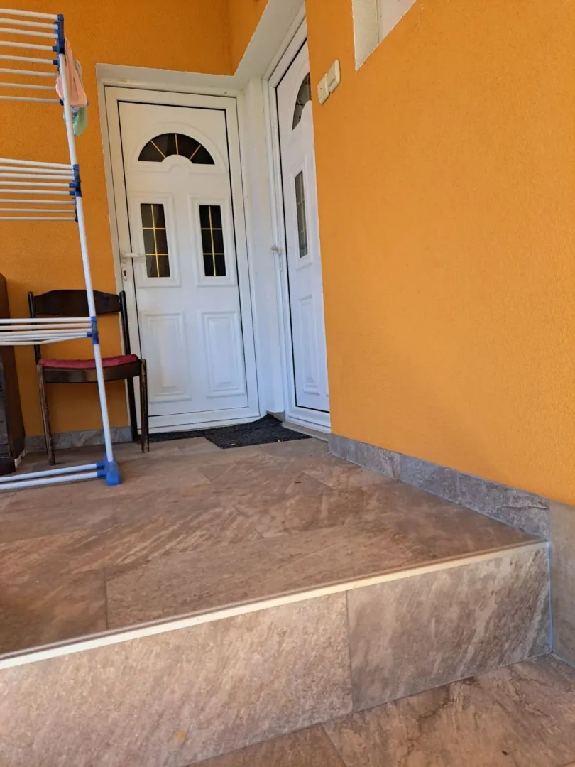 Entrance to the house with tiled stairs and white doors.