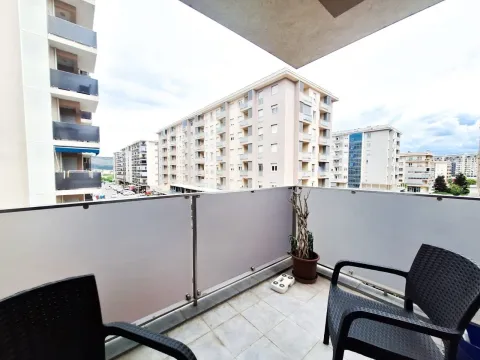 Namješten balkon sa staklenom ogradom i pogledom na naselje i okolne zgrade. - image 6