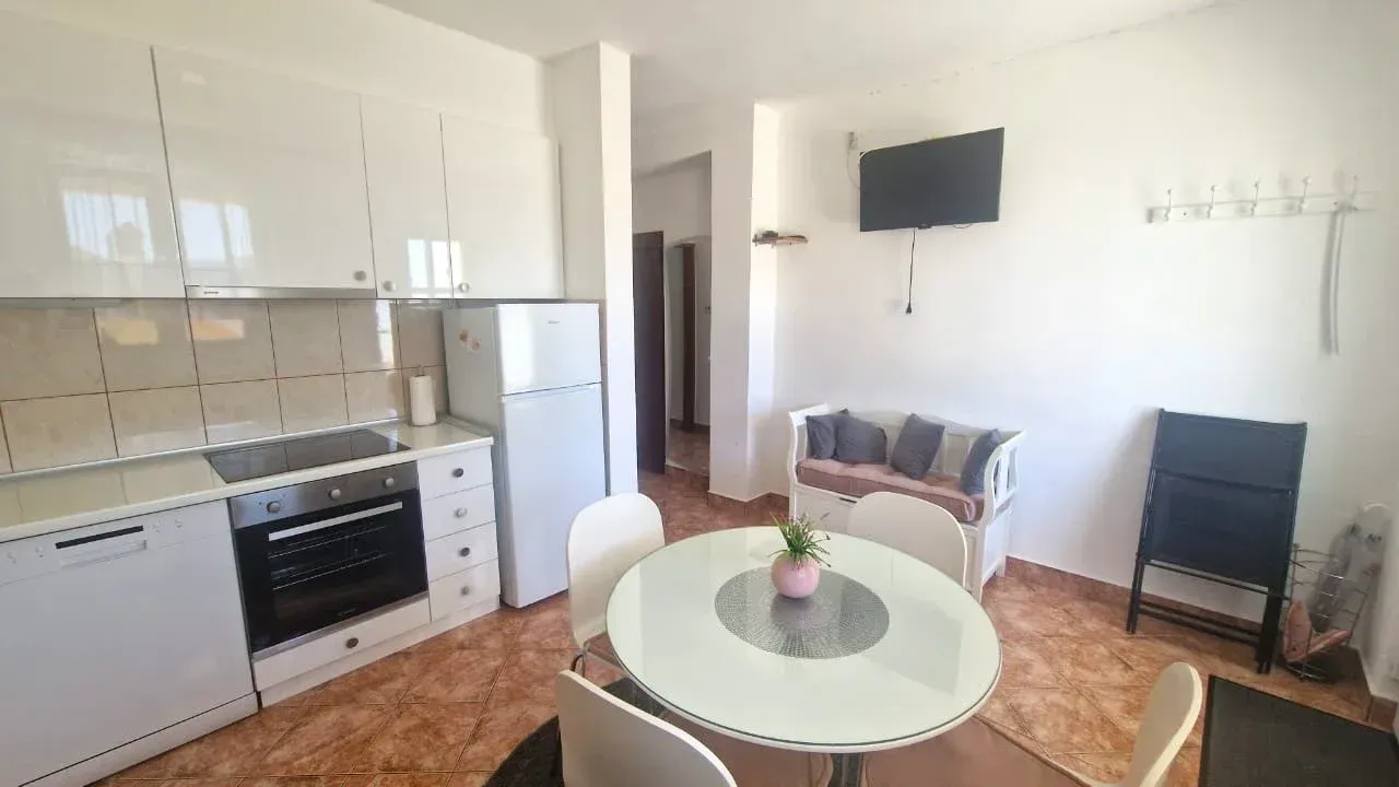 Kuhinja sa trpezarijom i bijelim elementima.