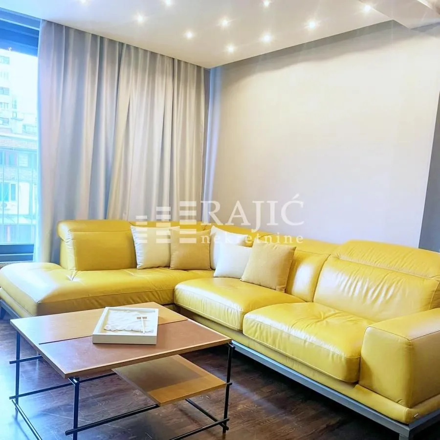 Living room with a yellow sectional sofa and a large window.