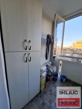 Zastakljeni balkon sa ormarom i pogledom na grad. - image 14