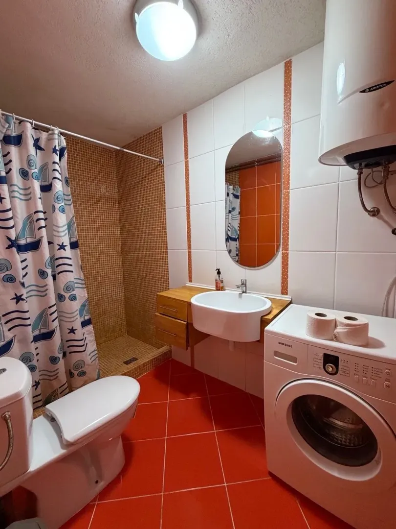 Bathroom with a shower cabin, washbasin, toilet, and washing machine.