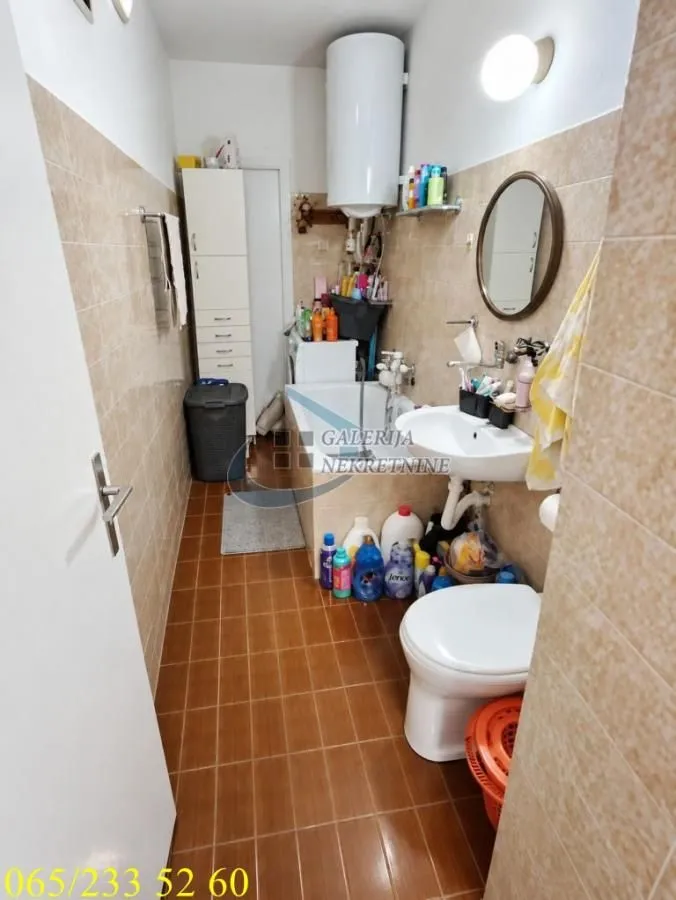 Small bathroom with a bathtub, washbasin, toilet, and water heater.